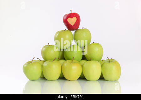 Apfel (Malus Domestica), Pyramide von grünen Äpfeln, oben auf einem roten mit Herz Stockfoto