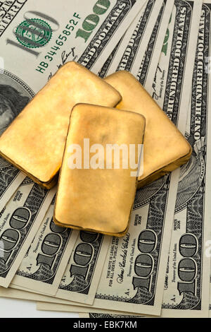 Goldbarren auf 100-Dollar-Scheine, die als Symbol für eine Investition in gold Stockfoto