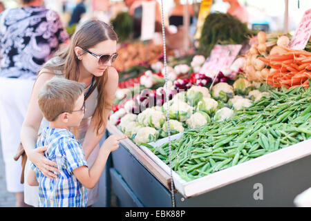 Mutter und Sohn, die Erbsen auf einem Gemüsemarkt kaufen Stockfoto