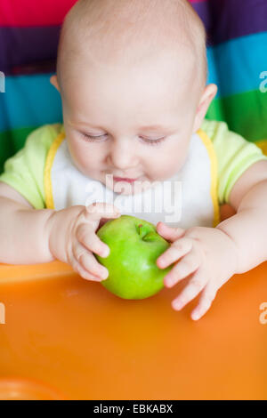 Entzückende Baby Essen im Hochstuhl. Babys erste feste Nahrung Stockfoto