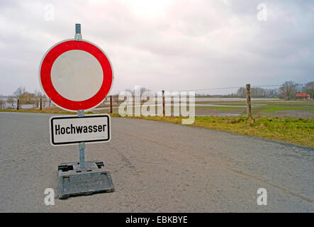 Verkehrsschild mit Hochwasser-Warnung und Durchgang nur für Residentsplaced in der Mitte eine asphaltierte Straße führt zu den Auen an der Weser in Neuenkirchen, Deutschland, Niedersachsen Stockfoto