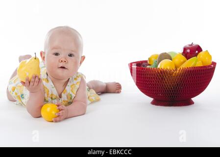 10 Monate altes Baby mit Korb mit Obst und Früchten in seinen Händen Stockfoto