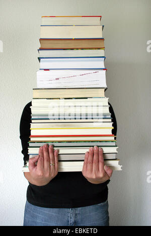 Frau, die einen Stapel Bücher Stockfoto