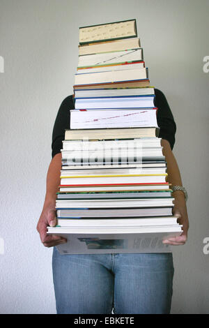 Frau, die einen Stapel Bücher Stockfoto