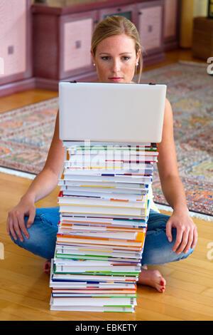 Studentin sitzt vor einem Stapel von Büchern und ein notebook Stockfoto