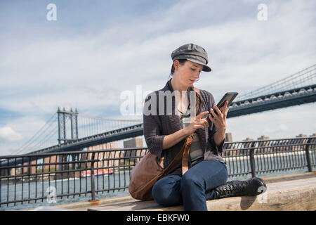 Frau mit TabletPC, Manhattan Bridge im Hintergrund, Brooklyn, New York State, New York City, USA Stockfoto