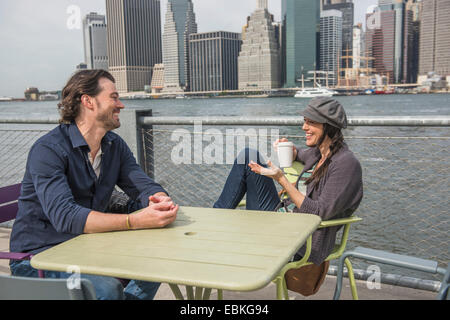 USA, New York State, New York City, Brooklyn, glückliches Paar sitzen und diskutieren mit Stadtbild im Hintergrund Stockfoto