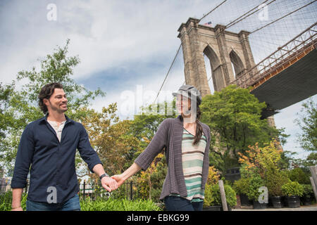 Glückliches Paar Hand in Hand und Fuß mit Brooklyn Bridge im Hintergrund Stockfoto