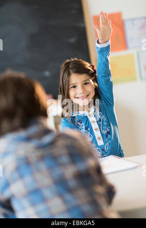Schüler (6-7) lernen im Klassenzimmer, Mädchen (6-7) heben die hand Stockfoto