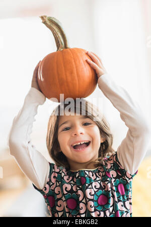 Porträt von glücklichen Mädchen (6-7) mit Kürbis auf Kopf Stockfoto