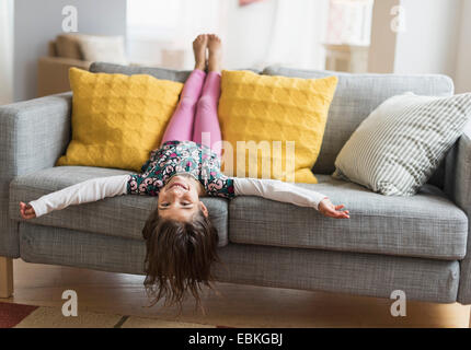 Mädchen (6-7) lag kopfüber auf sofa Stockfoto