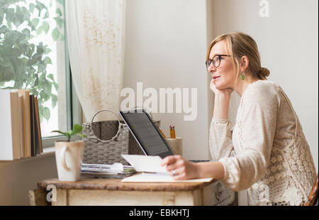 Frau am Schreibtisch sitzen und betrachten Stockfoto