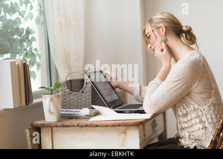 Frau am Schreibtisch sitzen und betrachten Stockfoto