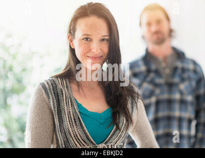 Lächelnde Frau, Blick in die Kamera, Mann im Hintergrund Stockfoto