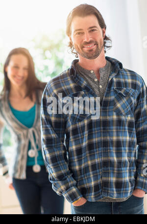 Lächelnder Mann, Blick in die Kamera, Frau im Hintergrund Stockfoto