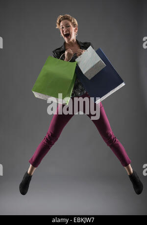 Studioaufnahme von Frau mit Einkaufstüten springen Stockfoto