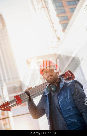 Porträt der Bauarbeiter tragen Stativ auf Schulter Stockfoto