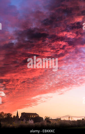 Ein dramatischer Himmel bei Sonnenuntergang läutet eine Änderung im Wetter den Sonnenuntergang hinter Malmesbury Abbey in Wiltshire. Stockfoto