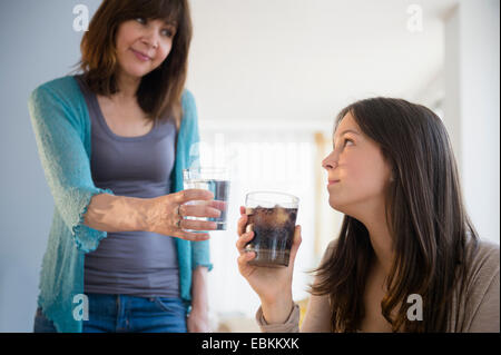 Mama, die Förderung der Teenager-Mädchens (14-15), Mineralwasser zu trinken Stockfoto