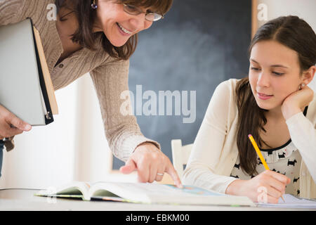 Lehrer, die Teenager-Mädchen (14-15) erklärt, wie man Hausaufgaben machen Stockfoto