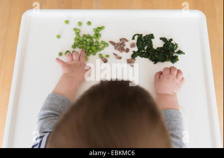 Babymädchen (12-17 Monate) Essen Steak, Spinat und grüne Erbsen Stockfoto