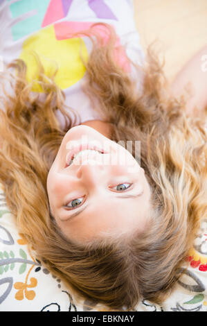Porträt des Lächelns Teenager-Mädchens auf Kissen liegend (12-13) Stockfoto