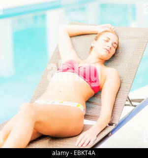 Frau liegend neben Schwimmbad Stockfoto