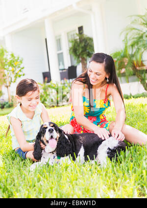 Mädchen (6-7) mit Mutter und Hund im Hinterhof, Jupiter, Florida, USA Stockfoto