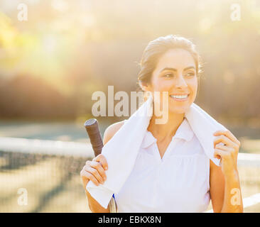 Porträt der lächelnde junge Frau mit Handtuch und Tennis Schläger Stockfoto