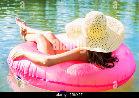 Rückansicht des jungen Frau mit Sonnenhut schwimmend auf Schwimmring Stockfoto