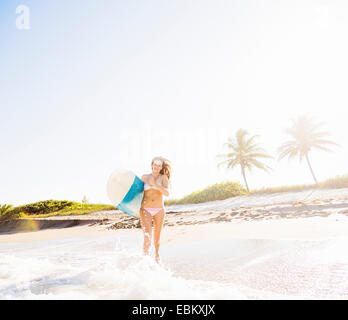 USA, Florida, Jupiter, junge Frau läuft in Brandung mit Surfbrett Stockfoto