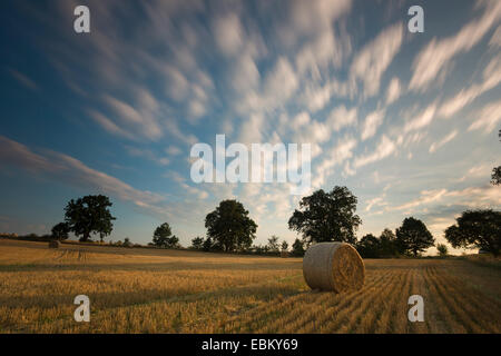 bewegte Wolken über ein Stoppelfeld mit Heuballen, Deutschland, Sachsen, Vogtlaendische Schweiz Stockfoto