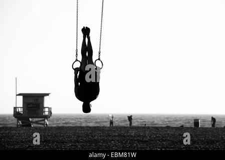 Silhouette einer Person schwingen an Ringen am Strand, Santa Monica Beach, Santa Monica, Los Angeles County, Kalifornien, USA Stockfoto