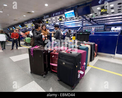 Passagiere mit Gepäck in der Schlange am Check-in Schalter am Flughafen Peking, China Stockfoto