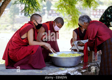 Mönche, die Verteilung von Reis zu einem Bedürftigen Besucher am Eingang eines Gebäudes im Punakha Dzong Festung, Punakha, Punakha Bezirk Stockfoto