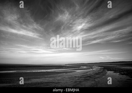 Eine schwarz-weiß Anzeigen des Strandes mit weißen Wolkenfetzen bei Holme als nächstes Meer, Norfolk, England, Vereinigtes Königreich. Stockfoto