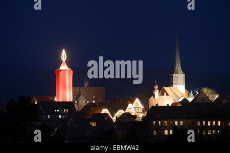 Nach der Eröffnung des Weihnachtsmarktes in Schlitz, Deutschland, 29. November 2014 ist die bekennende größte Kerze der Welt beleuchtet. Der 36 Meter hohe Turm auf dem historischen Marktplatz ist in rotes Tuch bedeckt. Auf ihrem Höhepunkt sind mehr als 110 Glühbirnen, angeordnet, um eine 6 Meter hohe Flamme ähneln. Foto: Arne Dedert/dpa Stockfoto