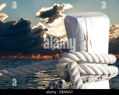 Poller am Sonnenuntergang mit den Booten auf See Stockfoto