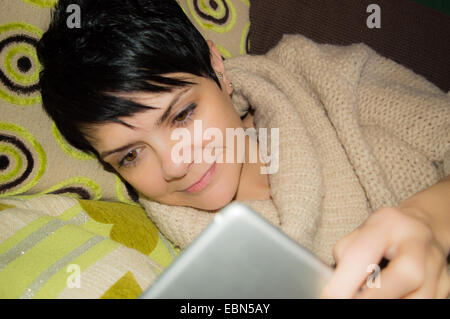 Moderne Art und Weise in Kontakt zu bleiben mit Ihren Lieben. Weibliche liegend lesen Ein ipad Stockfoto