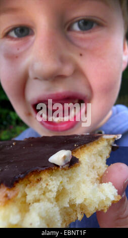 Junge hat ein Milchzahn einen Kuchen essen verloren. Stockfoto