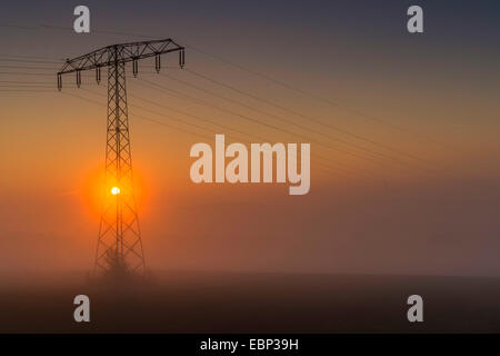 Strommast im morgendlichen Nebel bei Sonnenaufgang, Deutschland, Sachsen, Vogtland Stockfoto