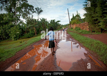 Frau mit Regenschirm und Handtasche ist auf dem Weg Fuß, die in Wasser, nach den letzten Regenfällen, Uganda, Jinja eingeweicht wird Stockfoto