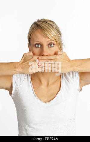 Junge, blonde Frau hielt sie die Hände auf den Mund, Deutschland Stockfoto