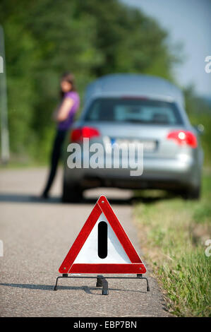 junges Mädchen mit einer Aufschlüsselung lehnt sich an ihrem Auto warten auf Hilfe Stockfoto