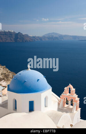 IA, Santorini, südliche Ägäis, Griechenland. Blick über das tiefblaue Wasser der Caldera, typische blau-Kuppel-Kirche im Vordergrund. Stockfoto