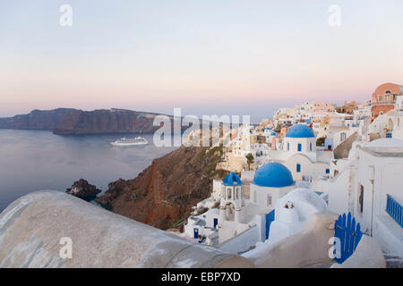 IA, Santorini, südliche Ägäis, Griechenland. Sehen Sie in der Morgendämmerung auf der fernen Insel Thirasia, Kreuzfahrtschiff in der Caldera. Stockfoto