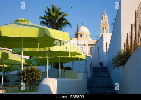 Fira, Santorini, südliche Ägäis, Griechenland. Blick entlang Weg zur Kuppel und Glockenturm der katholischen Kathedrale, Sonnenschirme Prominente. Stockfoto