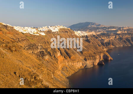 Imerovigli, Santorin, südliche Ägäis, Griechenland. Blick entlang der Klippen in Richtung Fira und die fernen Gipfel des Profitis Ilias, Sonnenuntergang. Stockfoto