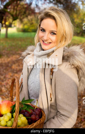 junge Frau hält einen Korb mit frischem Obst. Stockfoto