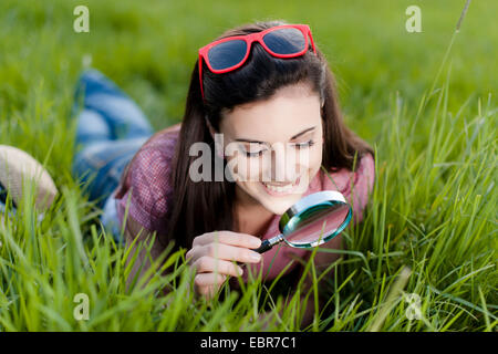 Frau mit Lupe auf dem Rasen liegend Stockfoto